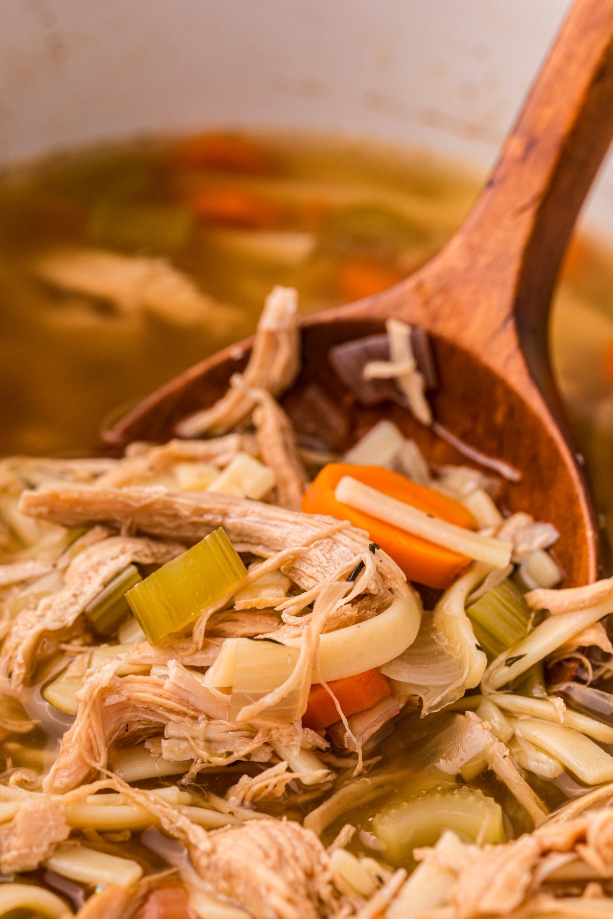 Zuppa di Tacchino e Pastina della Nonna a Cottura Lenta 2 Zuppa di tacchino e tagliatelle in slow cooker con un cucchiaio di legno.