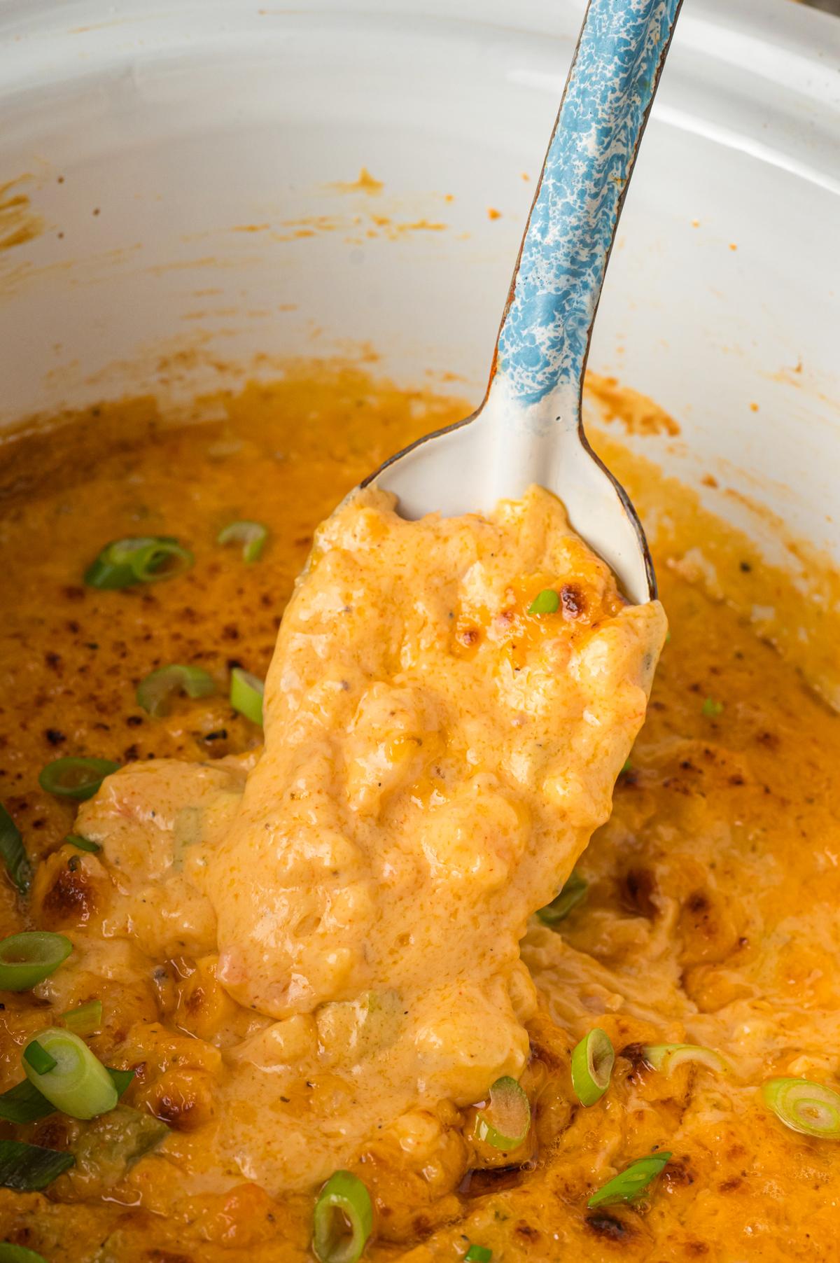 Salsa di Gamberetti Calda a Lenta Cottura 2 scooping hot shrimp dip out of slow cooker with a spoon.