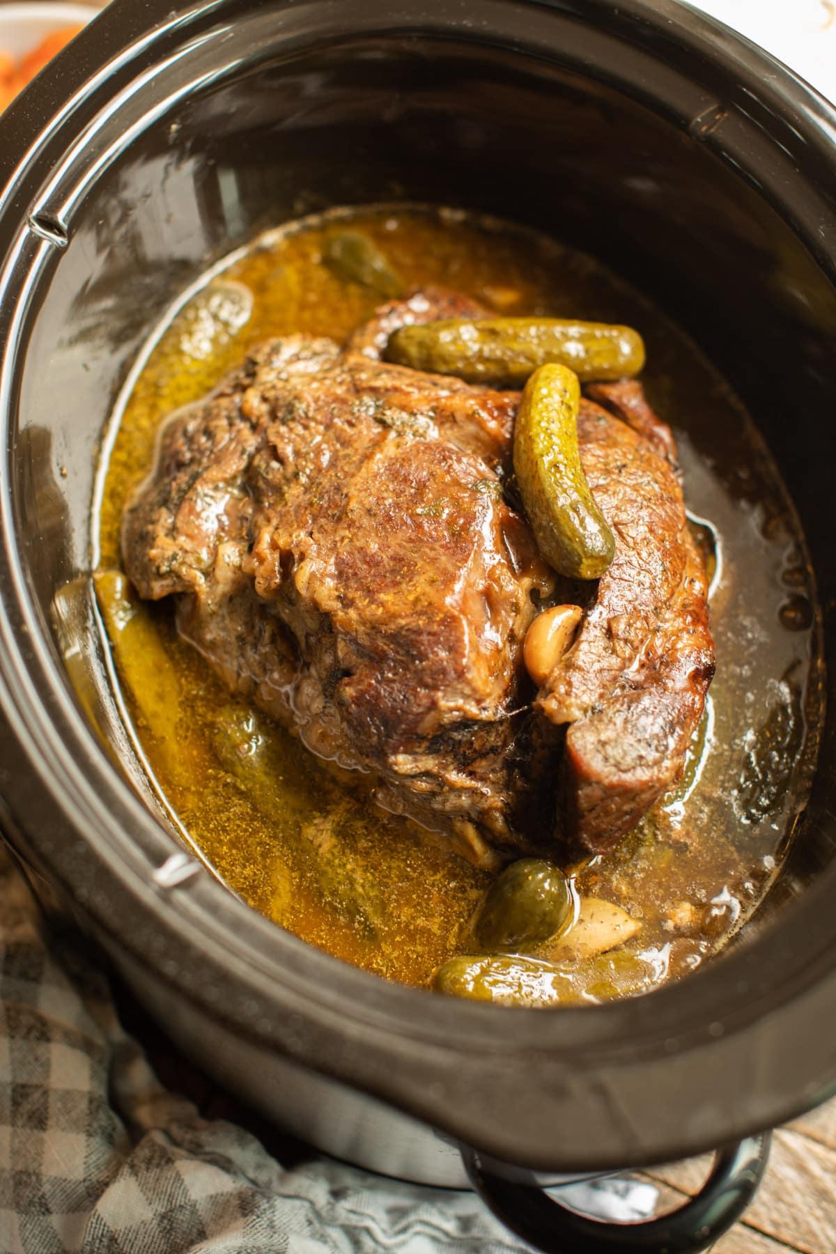 Brasato di manzo ai cetriolini e aneto appena cotto nella slow cooker, pronto per essere servito.