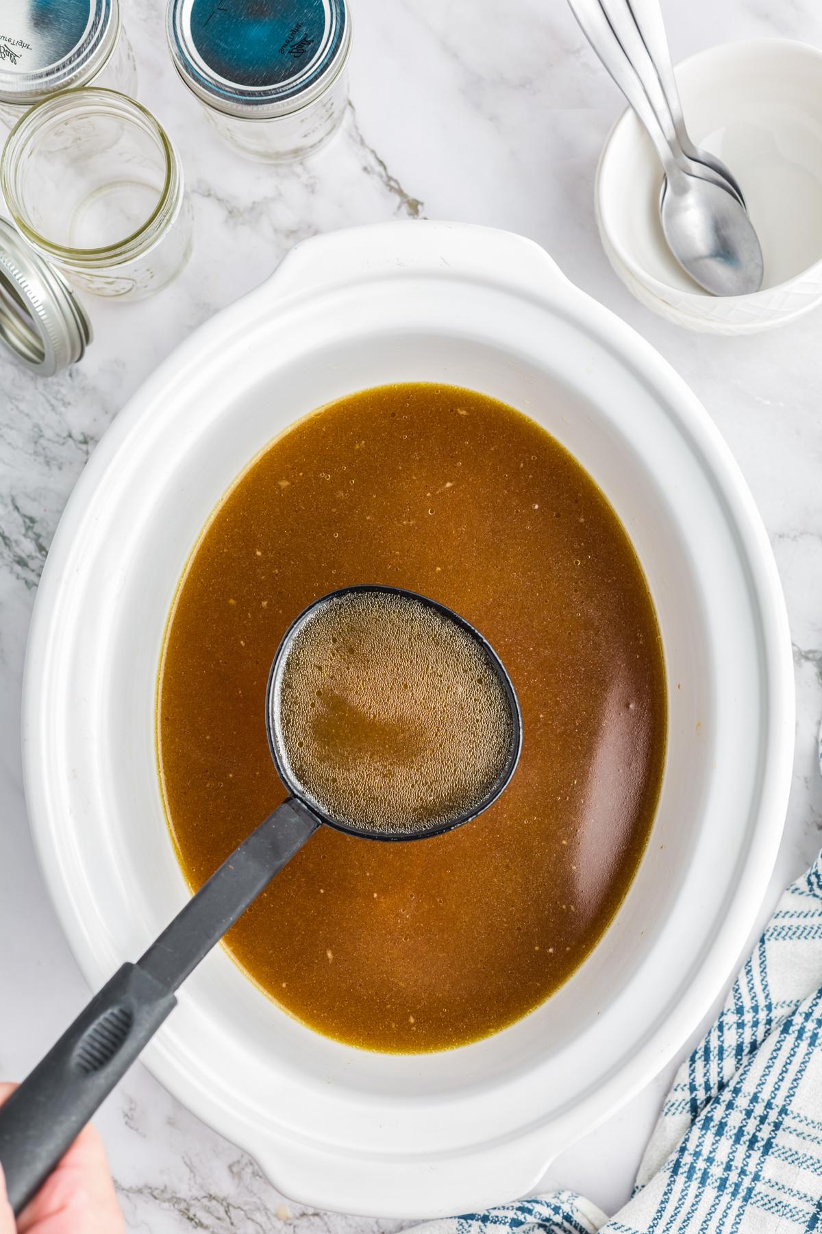 Brodo di Pollo a Cottura Lenta 2 Brodo di pollo cucinato lentamente in una slow cooker, con vapori che salgono, suggerendo calore e aroma.
