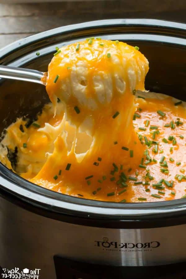 **Purè di Patate Formaggioso a Cottura Lenta** 2 Primo piano di purè di patate formaggiose servite con un cucchiaio di metallo.