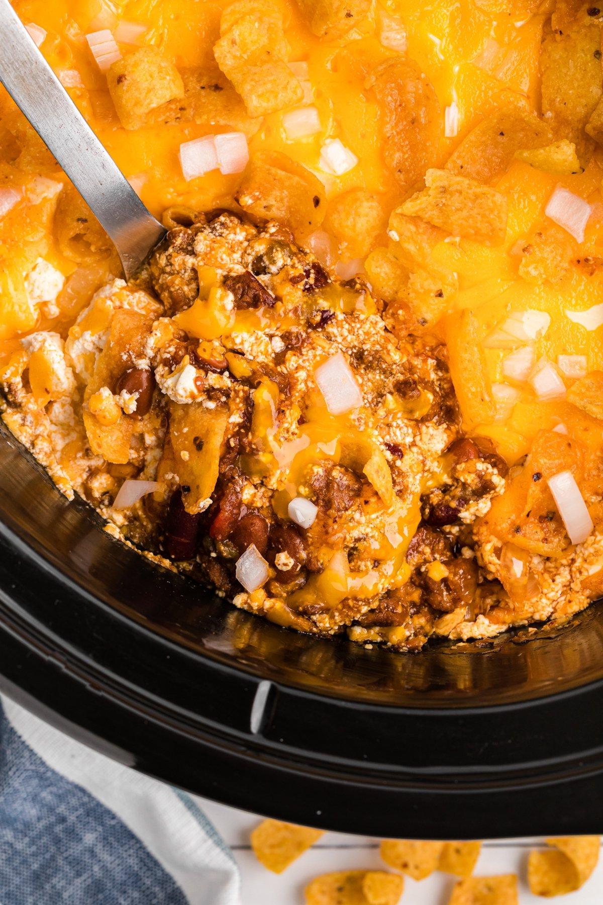 **Pasticcio di Chili a Cottura Lenta al Formaggio** 2 scooping out some chili cheese casserole from a crockpot.