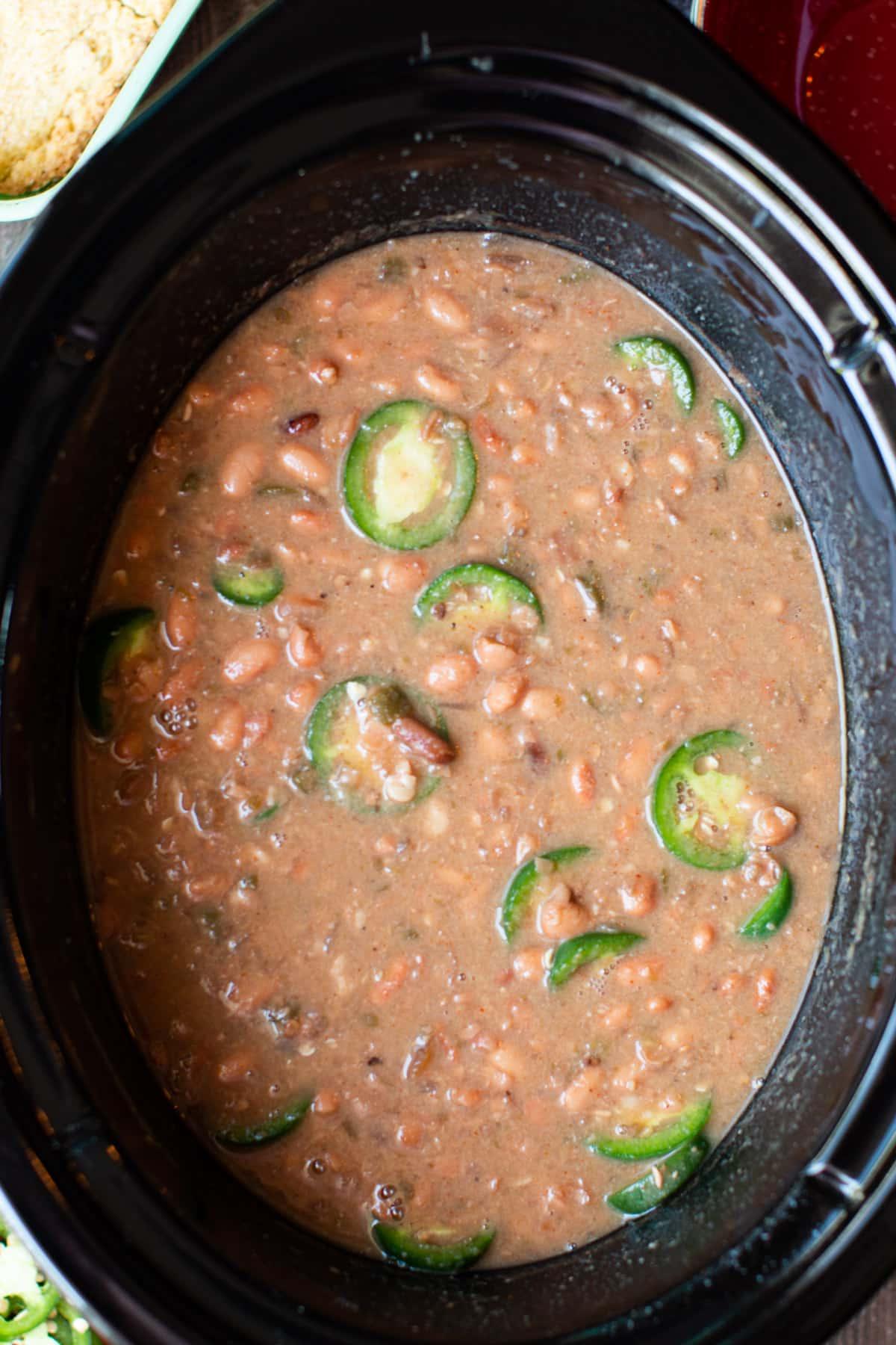 Fagioli Pinto Piccanti in Pentola a Cottura Lenta 2 Fagioli pinto piccanti con jalapeños freschi sopra, primi piani.