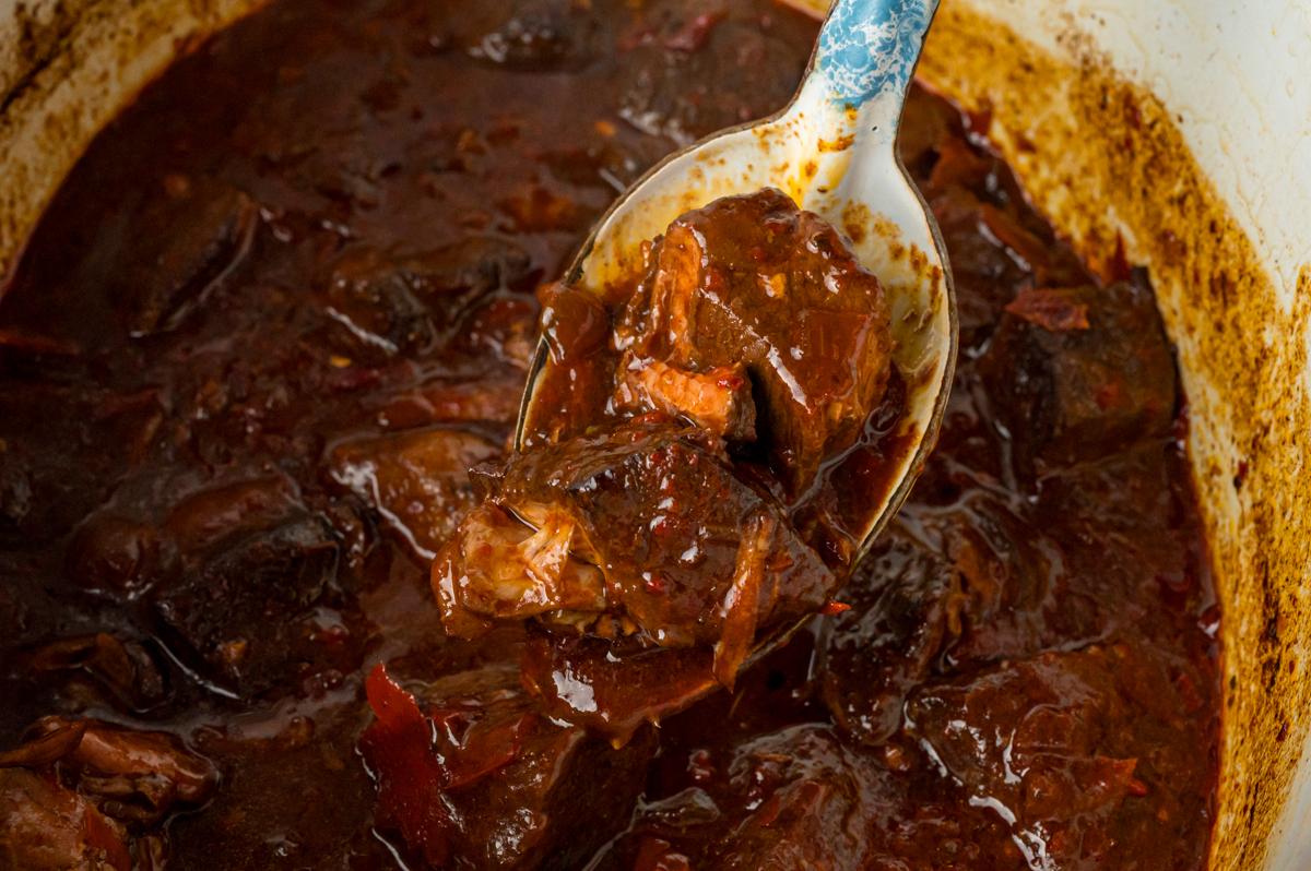 Close-up di un cucchiaio con una porzione di Chile Colorado al slow cooker.