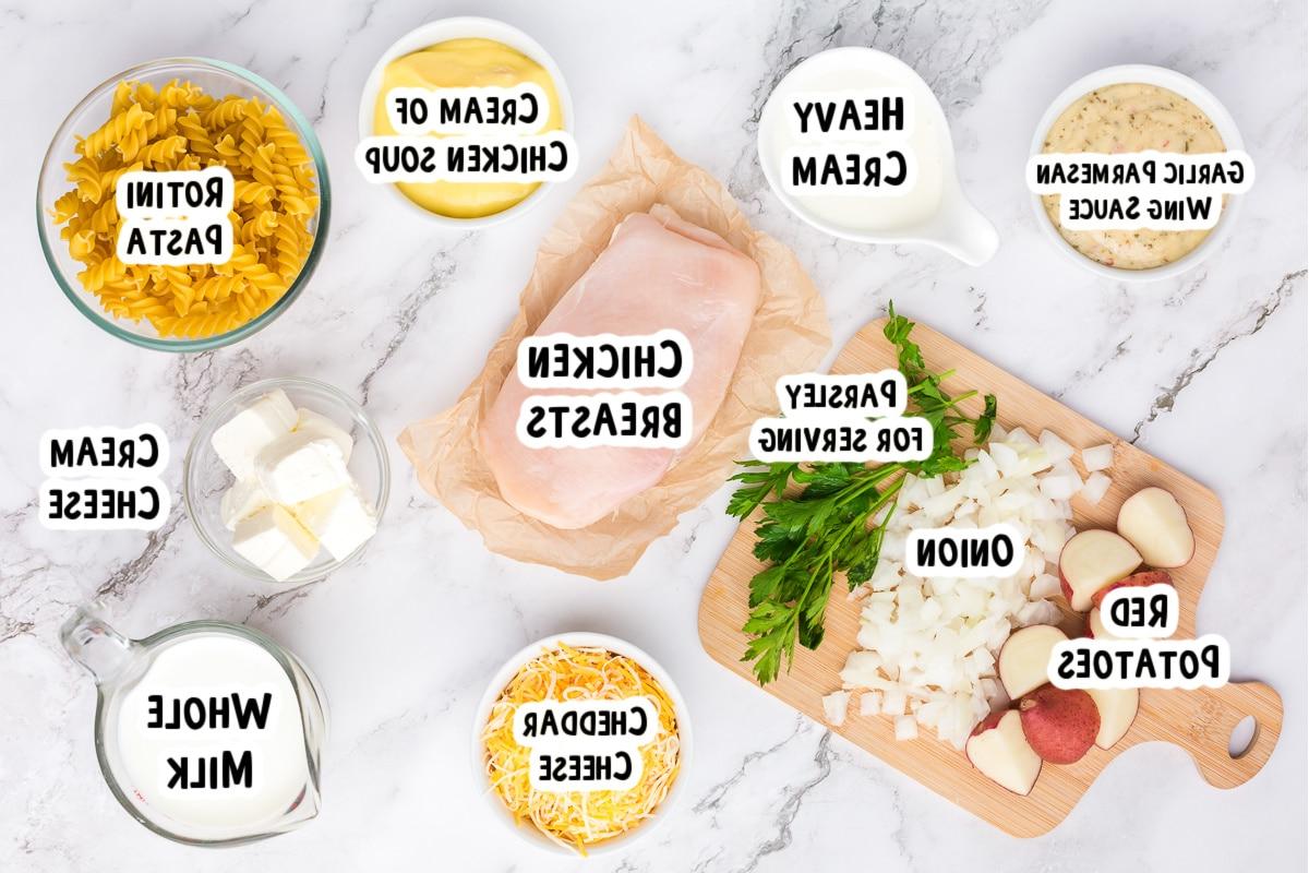 **Pollo all'Aglio e Parmigiano con Pasta a Cottura Lenta** 3 Ingredienti freschi e ben organizzati per la pasta cremosa al pollo e parmigiano all'aglio disposti su un tavolo da cucina.
