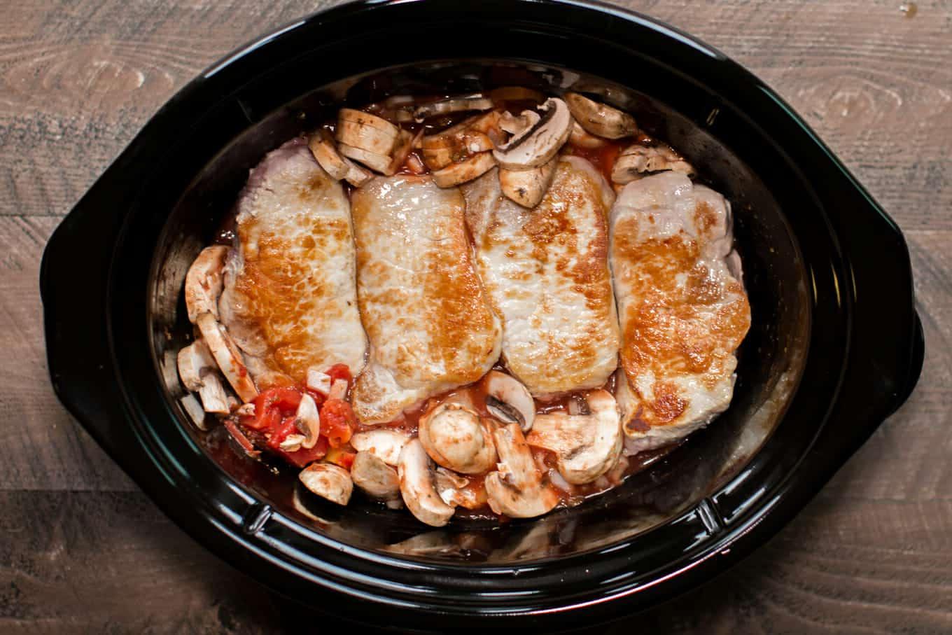 Costolette di Maiale alla Cacciatora a Cottura Lenta 3 Cotolette di maiale rosolate nella slow cooker con funghi e pomodori.