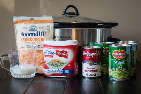 **Gratin di Fagiolini al Formaggio a Cottura Lenta** 3 Ingredienti base per la casseruola di fagiolini: fagiolini, zuppa di funghi, cipolle fritte, formaggio cheddar grattugiato e latte, tutti disposti davanti a una slow cooker, pronti per essere combinati.
