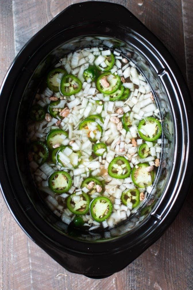 Fagioli Pinto Piccanti in Pentola a Cottura Lenta 4 Cipolle, fagioli pinto e jalapeños nella slow cooker, pronti per la cottura.