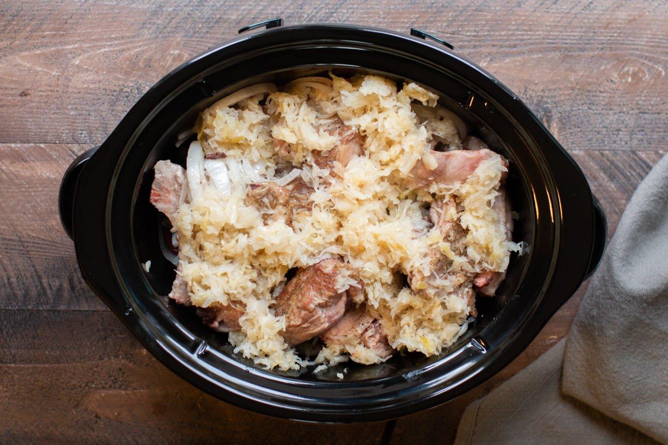 Costine, Patate e Crauti Cotte Lentamente 4 Costine, crauti, patate e cipolle non ancora cotti nella slow cooker, pronti per la cottura lenta.