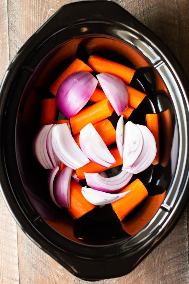 Pollo Intero in Slow Cooker 4 Carote e cipolle sul fondo della slow cooker.