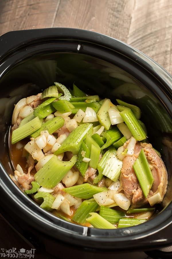 Pollo al Pepe Nero in Pentola a Cottura Lenta {Congelabile} 4 slow cooker with raw chicken, onion, and celery and black pepper.