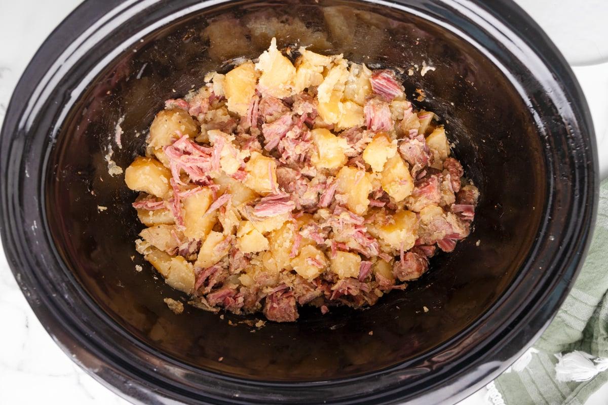 Pasticcio di Manzo Salmistrato a Cottura Lenta 5 Manzo salato sfilacciato e patate in una pentola a cottura lenta.