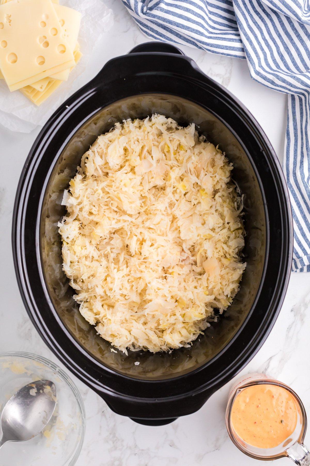 Casseruola di Pollo alla Reuben a Cottura Lenta 5 Crauti aggiunti sopra il pollo nella slow cooker.