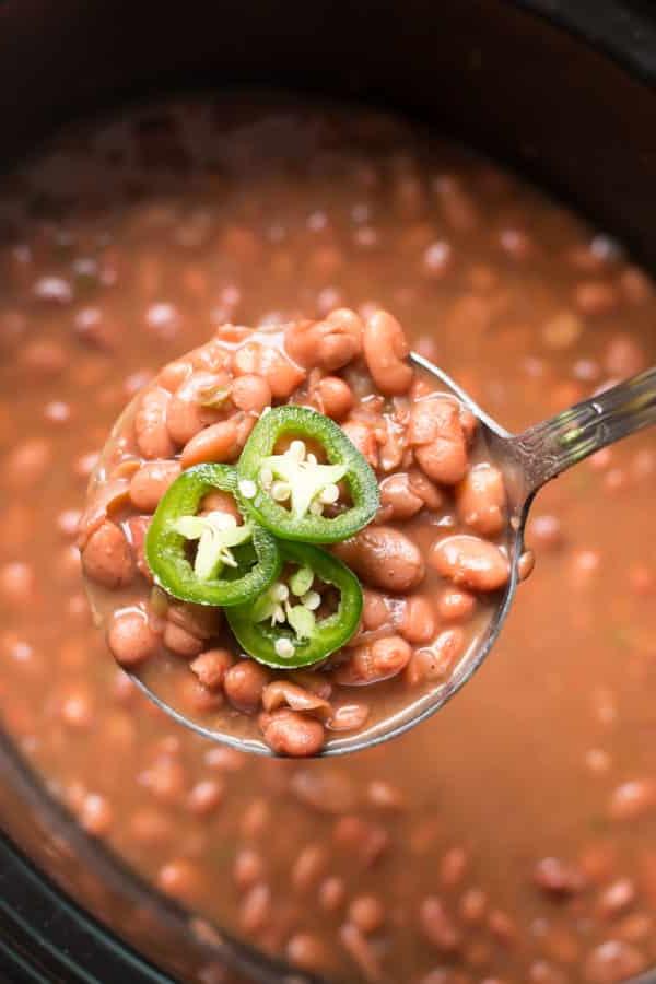 Fagioli Pinto Piccanti in Pentola a Cottura Lenta 5 Fagioli pinto cremosi su un mestolo che esce dalla slow cooker.