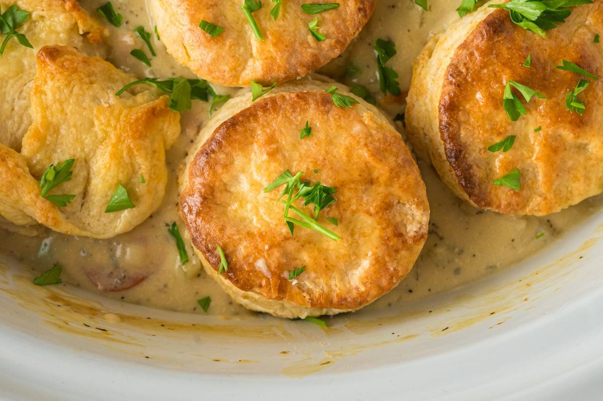 Facile Pasticcio di Pollo Cotto Lentamente con Focaccine 5 Primo piano della torta rustica di pollo con biscotti in una pentola a cottura lenta bianca.