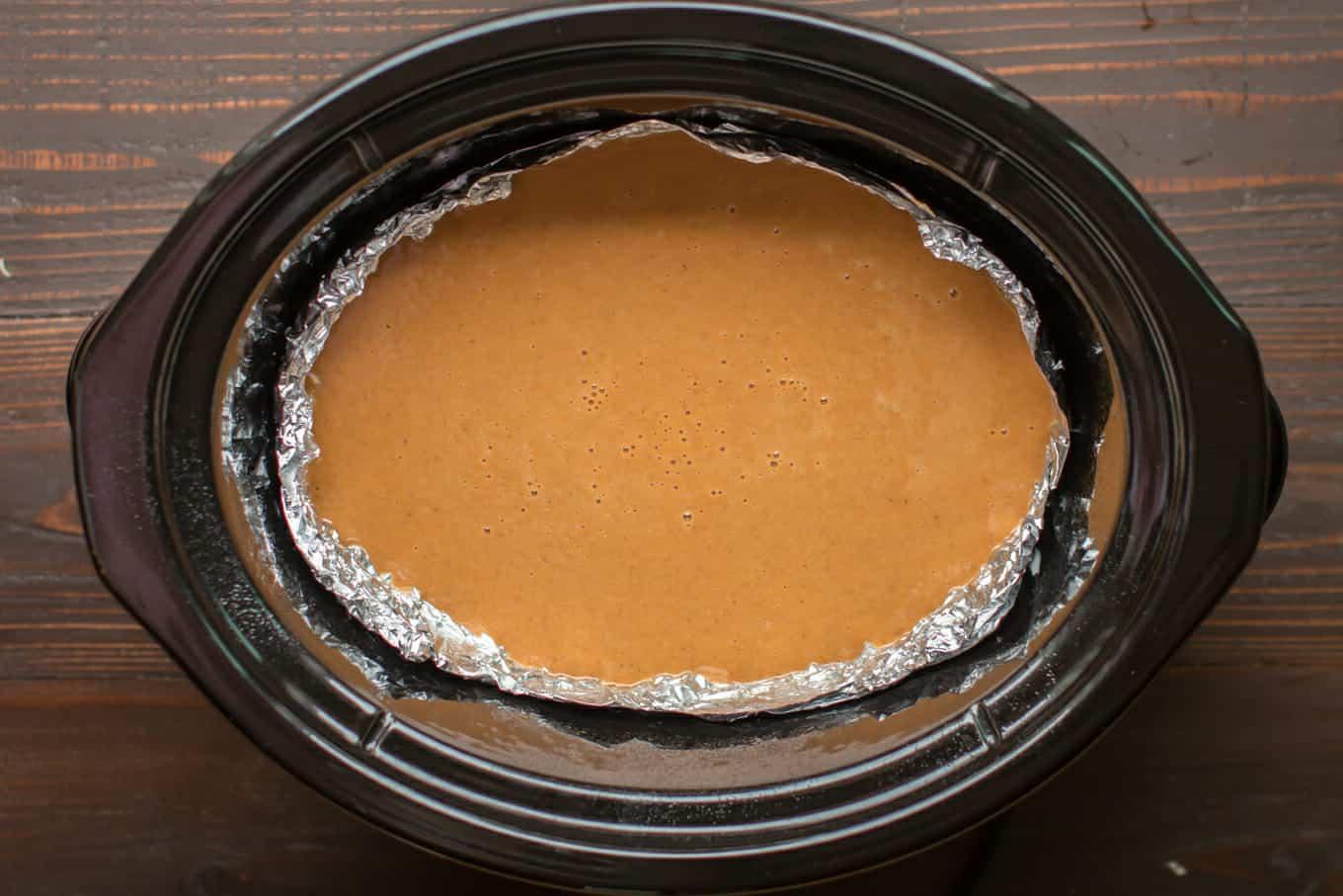 Torta di Zucca Senza Crosta allo Zucchero di Canna a Cottura Lenta 5 Ripieno di torta di zucca cruda nella slow cooker (rivestita di alluminio).