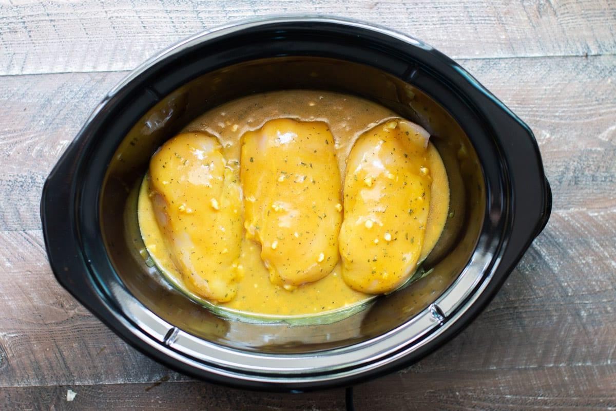 Pollo al Miele e Senape in Pentola a Cottura Lenta 5 Salsa casalinga di miele e senape versata sui petti di pollo nella slow cooker.