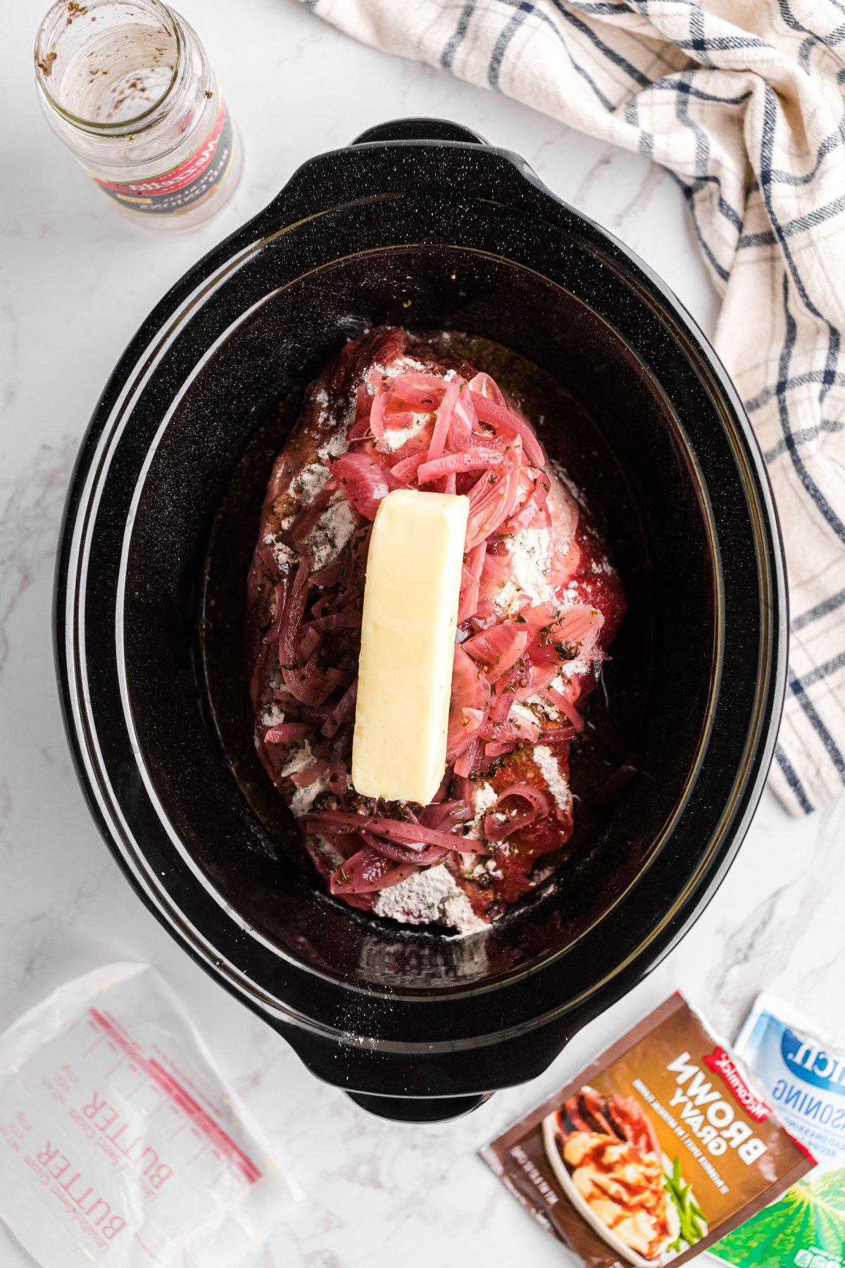 Cipolle sottaceto e burro aggiunti all'arrosto di manzo condito nella slow cooker.