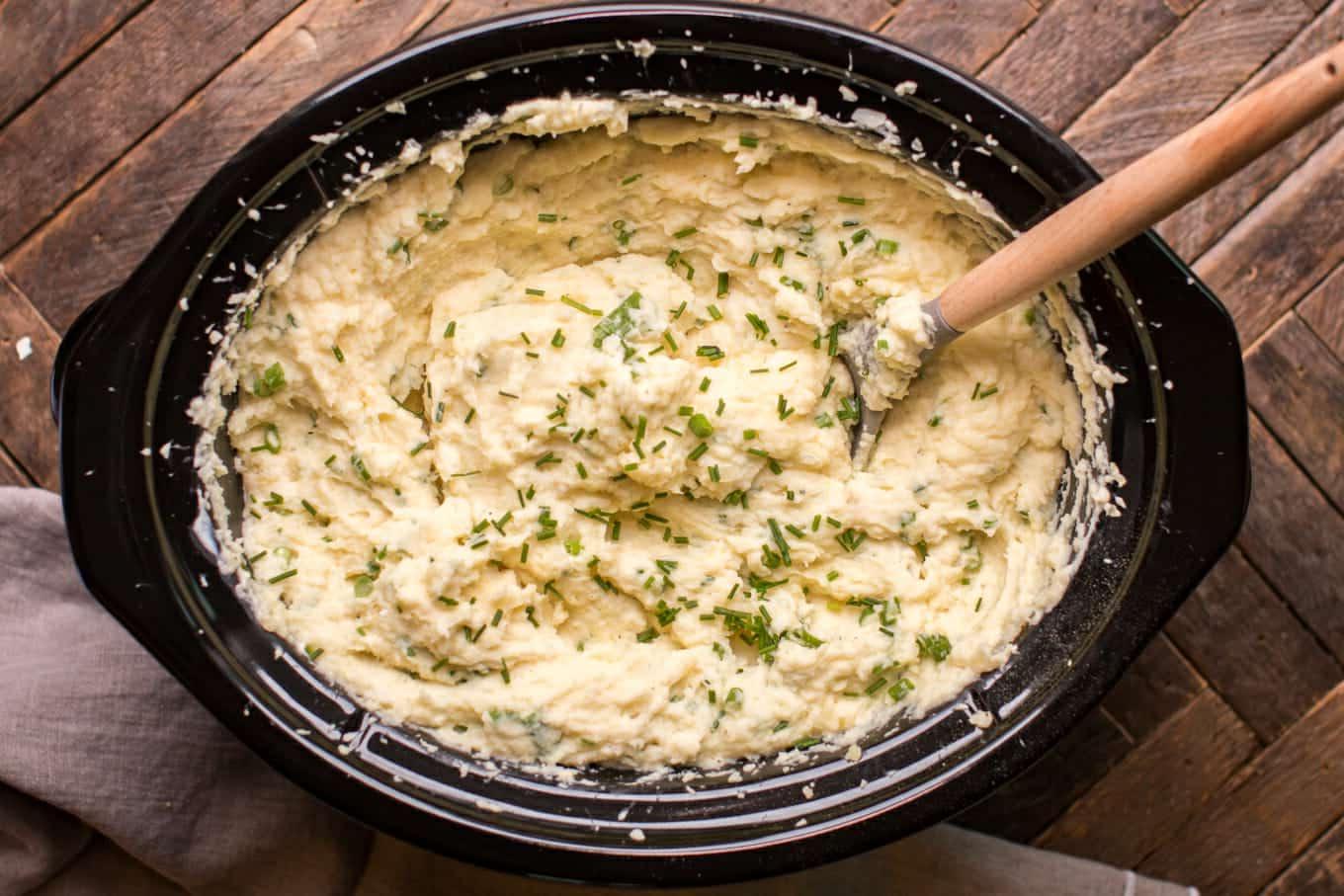 Purè di patate a cottura lenta con panna acida e cipolla 5 Patate in purea con panna acida e cipolla appena cotte, con un cucchiaio di legno inserito.