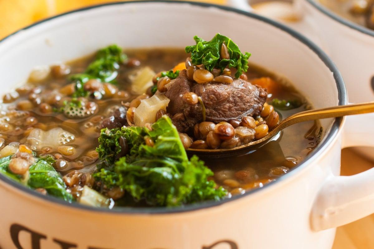 close-up of slow cooker beef and lentil soup in a bowl.