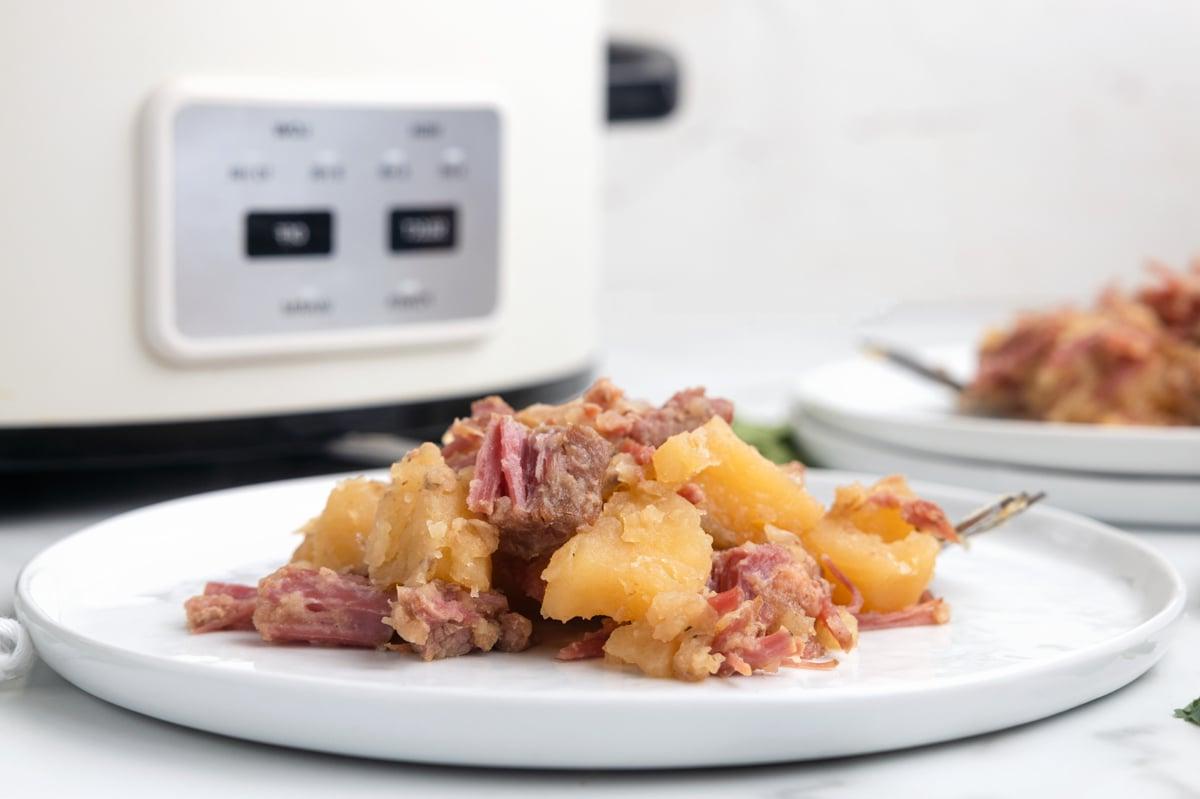 Pasticcio di Manzo Salmistrato a Cottura Lenta 6 Piatto di manzo salato e cavolo davanti a una pentola a cottura lenta.