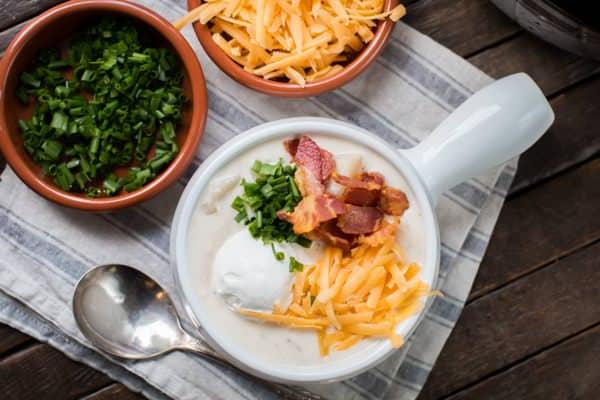 Zuppa Ricca di Pollo, Bacon e Patate in Slow Cooker 6 Zuppa di patate al forno con pollo, guarnita con formaggio, panna acida e cipollina verde in una ciotola.