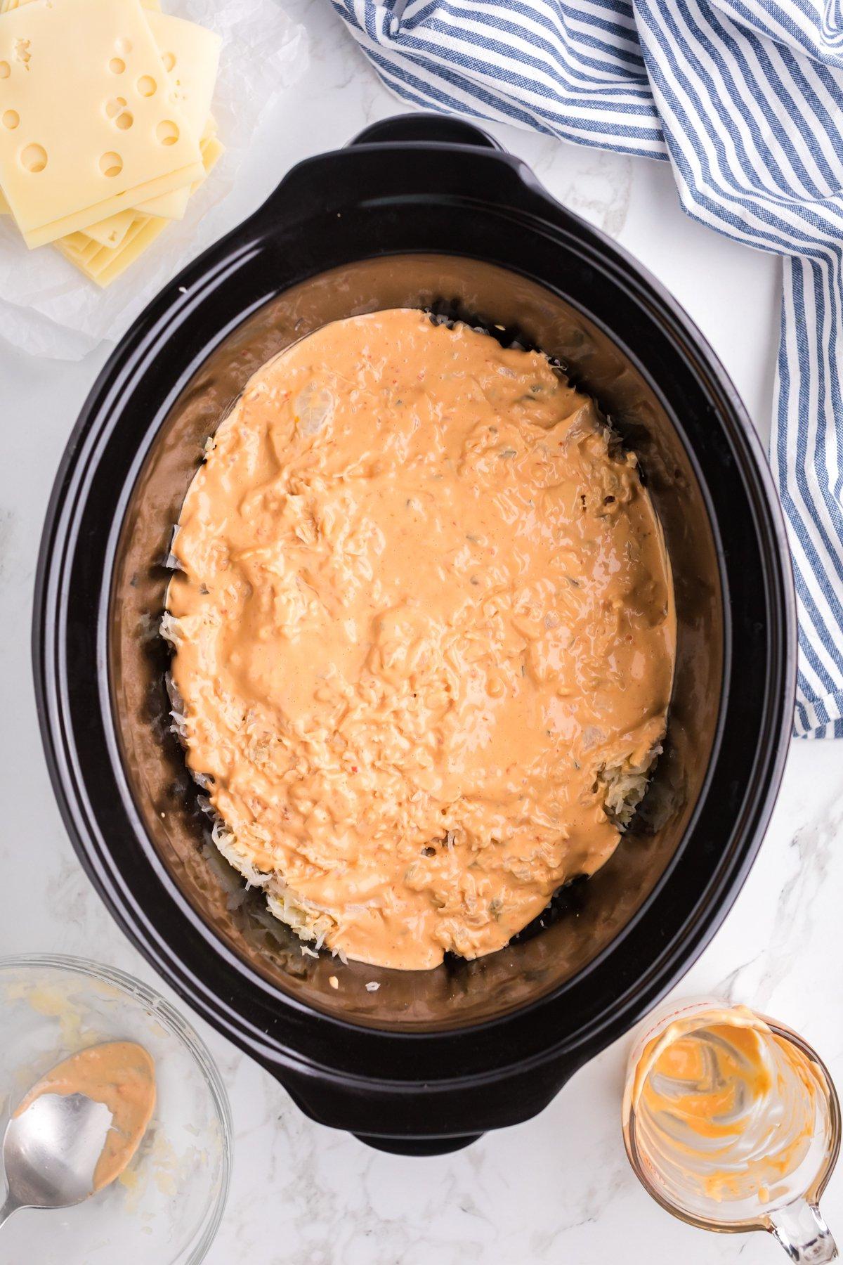 Casseruola di Pollo alla Reuben a Cottura Lenta 6 Salsa Thousand Island sopra pollo e crauti nella slow cooker.