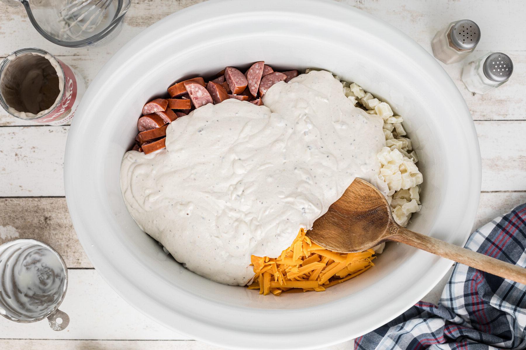 Sformato di Kielbasa e Hashbrowns in Cottura Lenta 6 Salsa cremosa aggiunta agli altri ingredienti nella slow cooker.