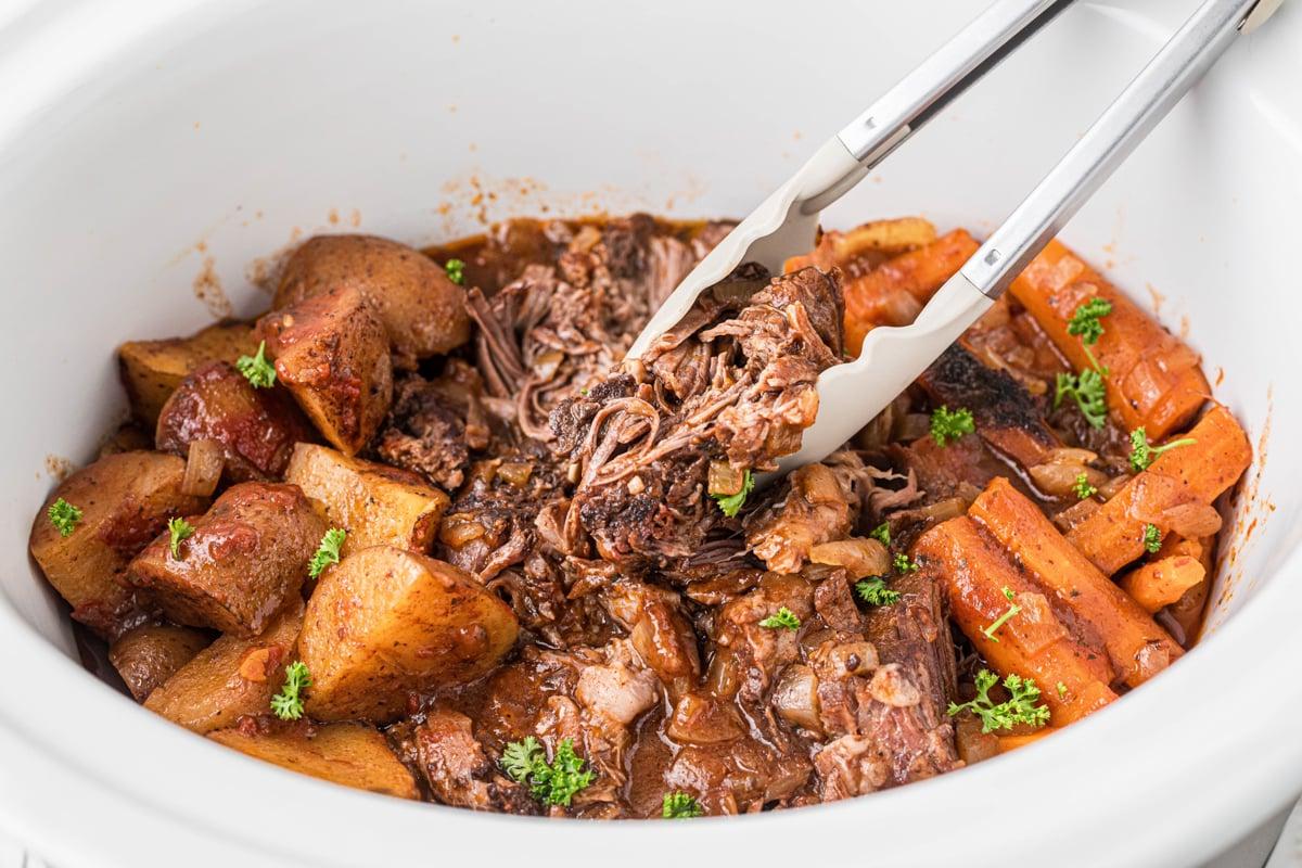 **Stracotto all'Italiana** 6 pinze che prendono del manzo brasato all'italiana in slow cooker.