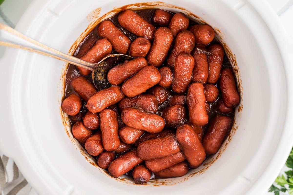 **Wurstel Piccoli al Burro di Mele in Slow Cooker** 6 Salsiccine mini al burro di mele nella slow cooker, servite con un cucchiaio.