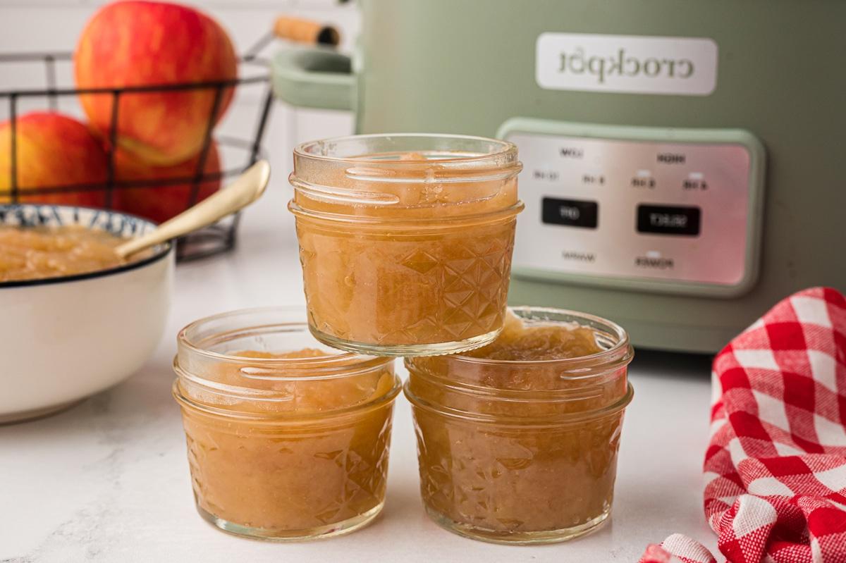 Salsa di mele a cottura lenta 6 3 barattoli di salsa di mele davanti alla slow cooker.