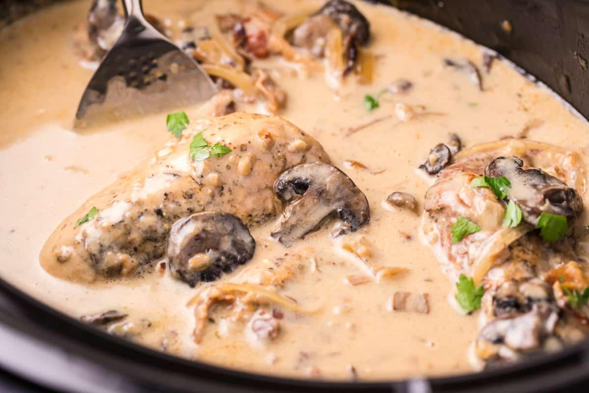 Pollo al Marsala in pentola a cottura lenta 6 Vista ravvicinata del pollo al Marsala nella slow cooker con prezzemolo sopra.