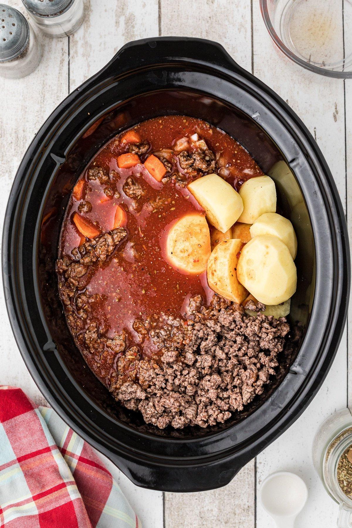 **Stufato del Poverello Cotto Lentamente** 6 Salsa di pomodoro versata su carne e verdure nella pentola a cottura lenta.