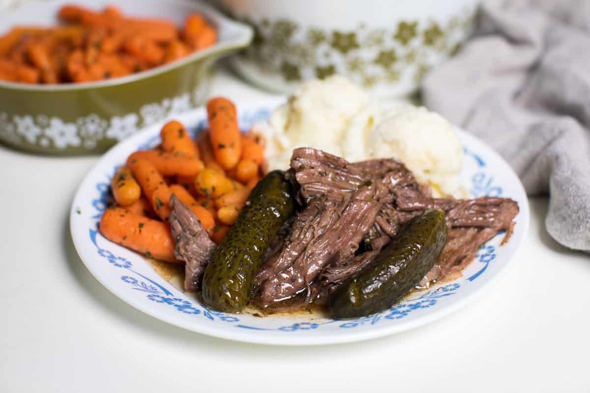 Brasato di manzo sfilacciato con cetriolini sott'aceto su un piatto, pronto per essere gustato.