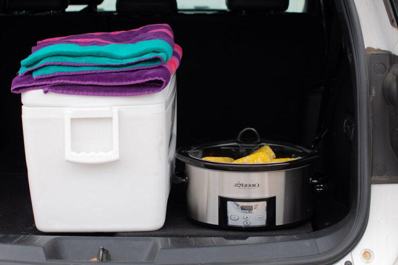 11 Contorni Facili con la Slow Cooker 7 Frigorifero bianco con asciugamani sopra e una slow cooker con pannocchie di mais al suo interno.