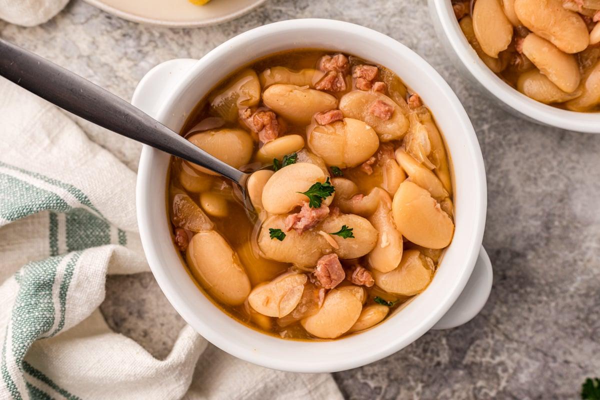 Fagioli di Lima a Cottura Lenta 7 Vista dall'alto di fagioli di lima in slow cooker in una ciotola con un cucchiaio.