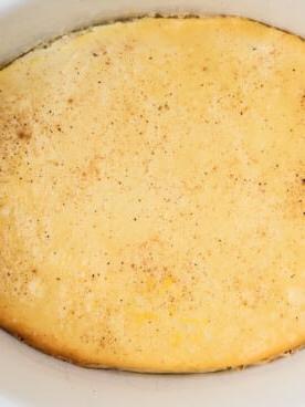 Primo piano del budino al forno in un crockpot bianco.