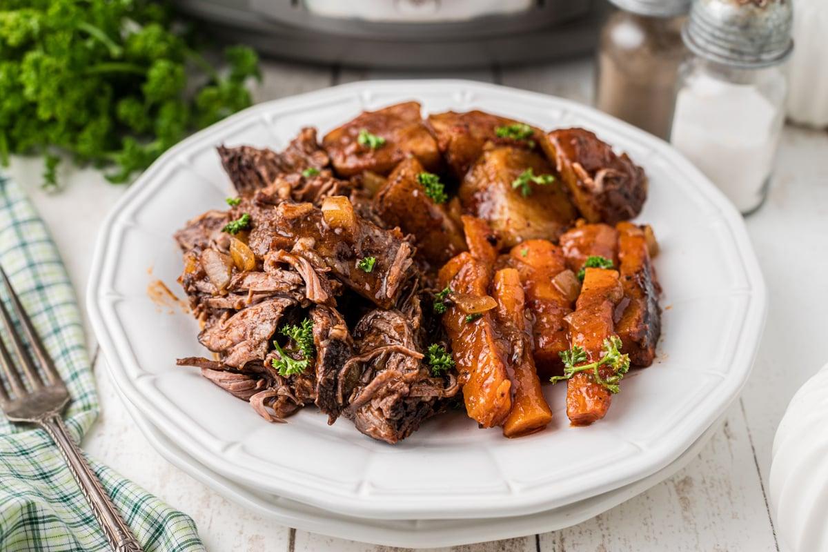 **Stracotto all'Italiana** 7 piatto di manzo brasato all'italiana in slow cooker su una pila di piatti.