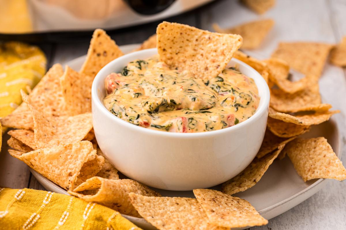 Salsa di Formaggio e Spinaci a Lenta Cottura 7 ciotola di queso dip con patatine intorno.