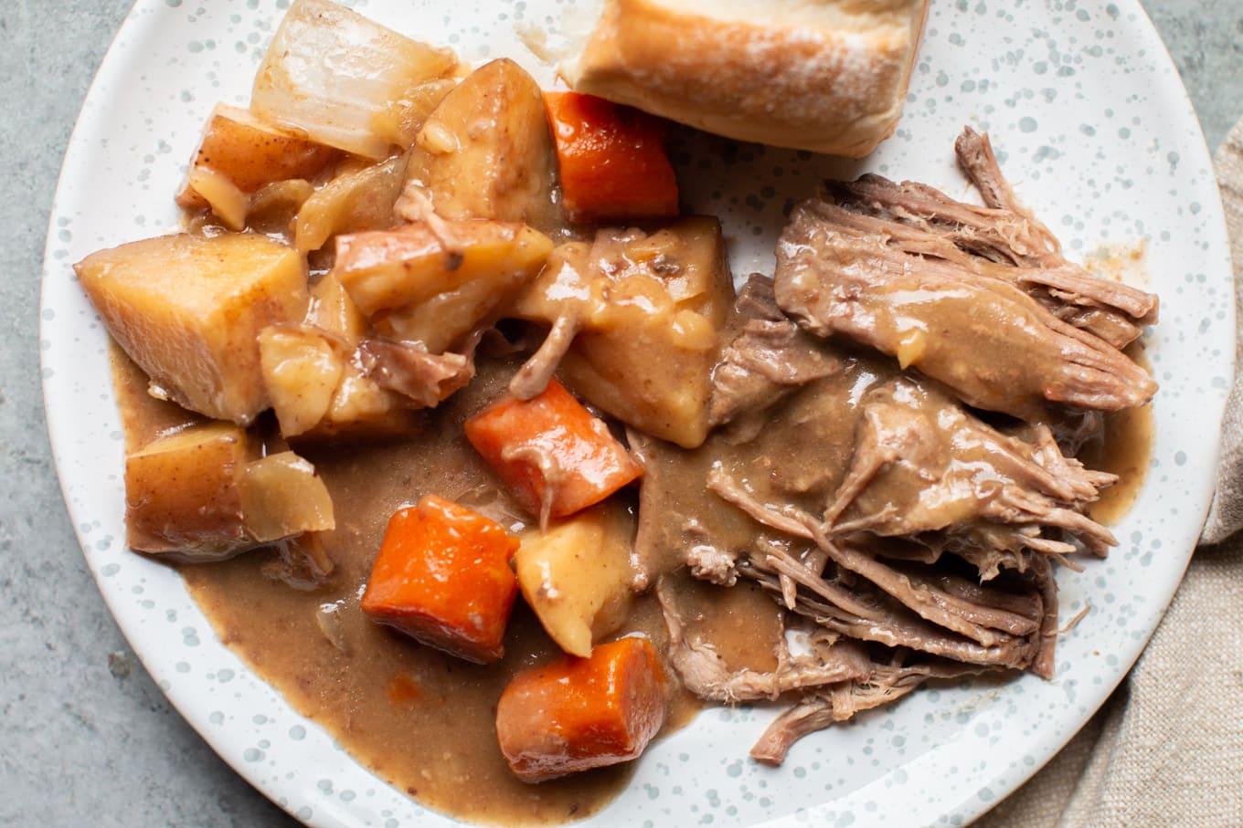 Brasato della Nonna per la Cena {con sugo che si forma da sé} 7 Arrosto di manzo con verdure, panino e sugo su un piatto maculato.