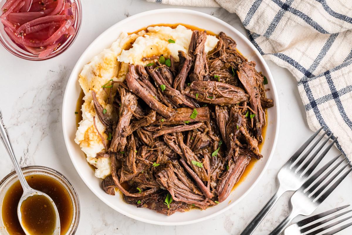Arrosto di manzo cotto in slow cooker su un piatto con purè di patate.