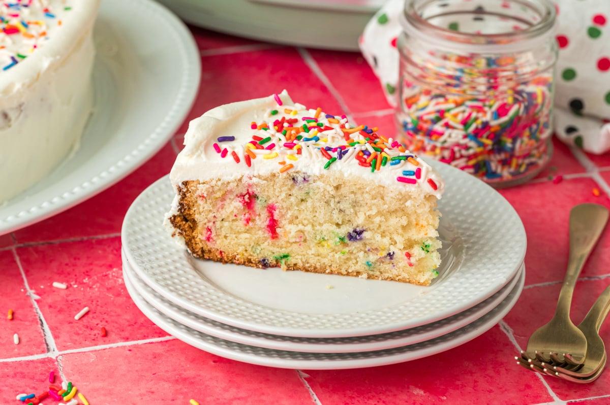 Fetta di torta di compleanno cotta nella slow cooker su una pila di piatti.