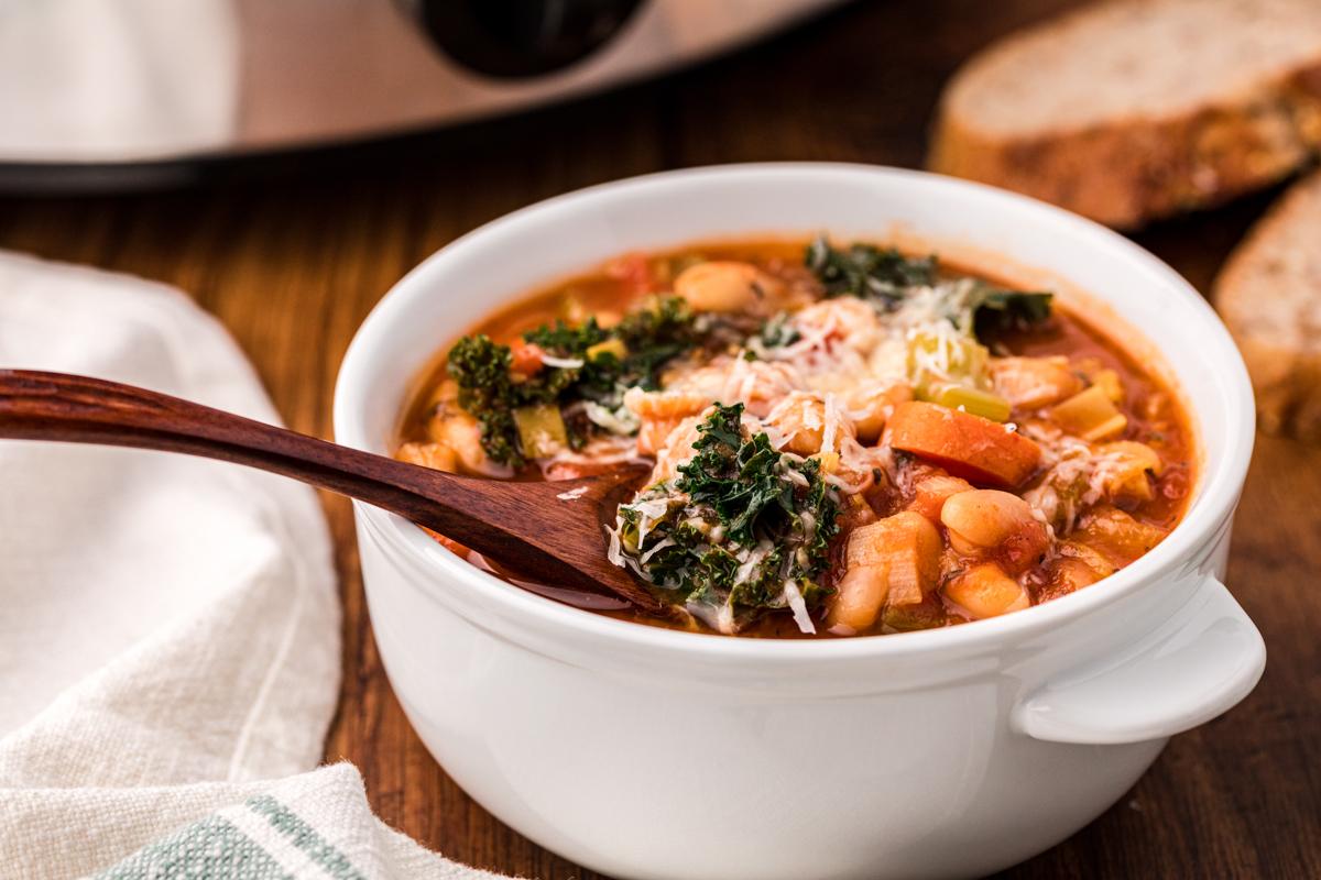Zuppa Ribollita a cottura lenta 7 bowl of ribollita soup with small wooden spoon in it.
