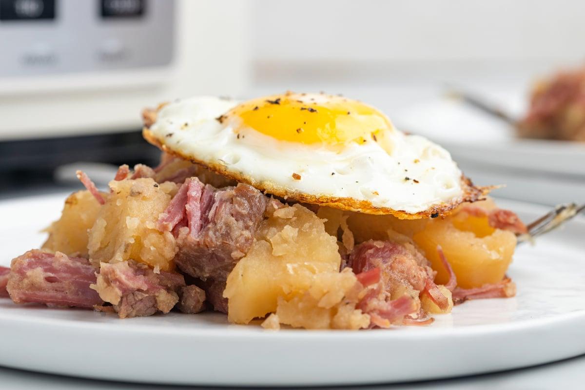 Pasticcio di Manzo Salmistrato a Cottura Lenta 7 Manzo salato e cavolo su un piatto con un uovo fritto in cima.