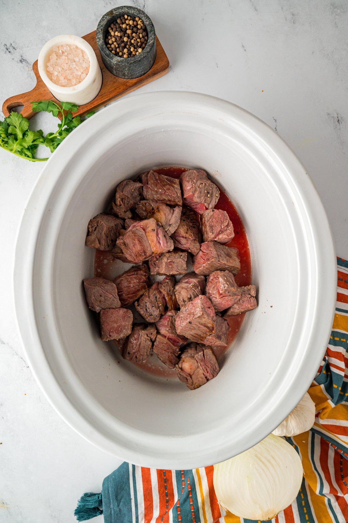 Manzo aggiunto a un slow cooker.