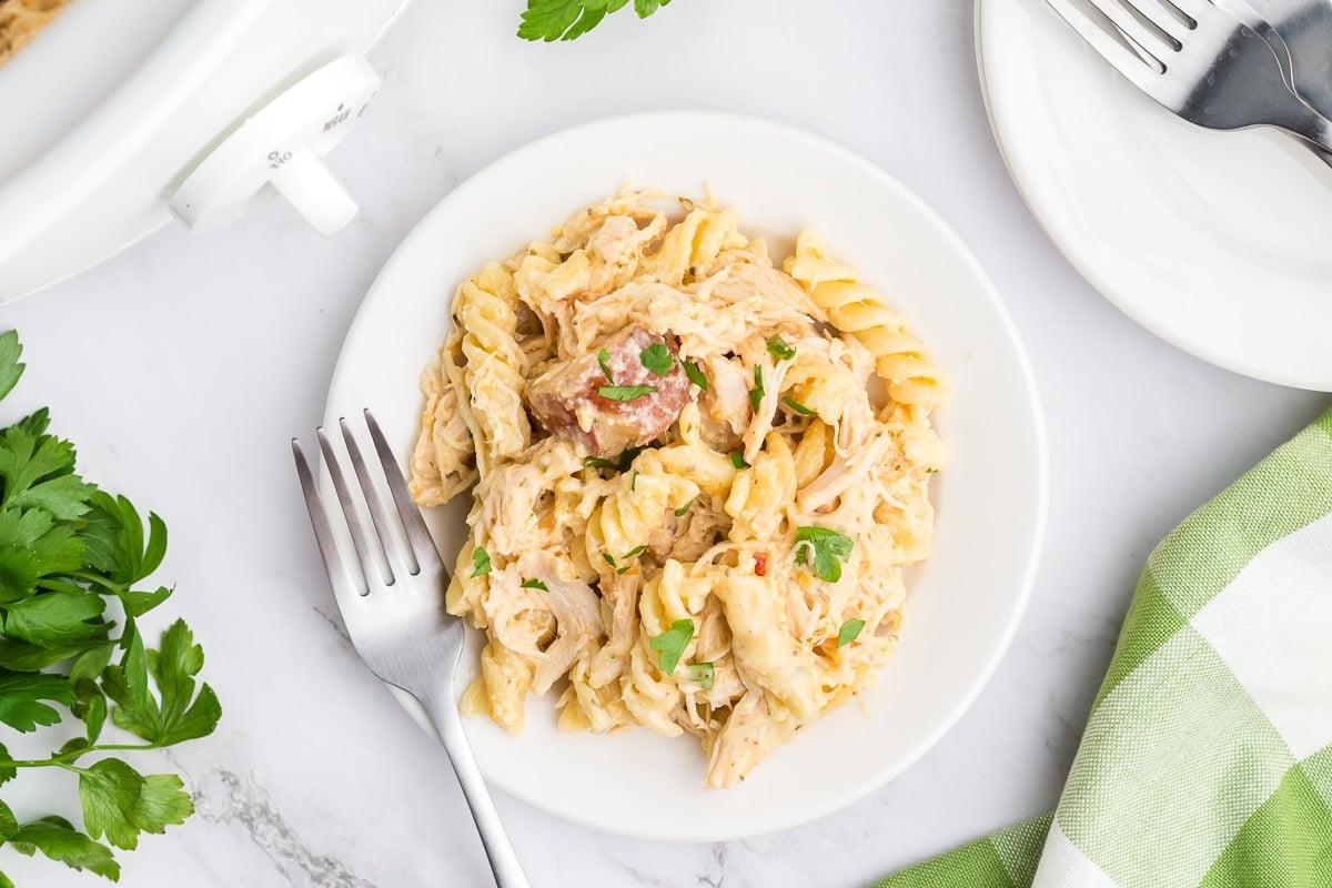 **Pollo all'Aglio e Parmigiano con Pasta a Cottura Lenta** 7 Un piatto singolo di pasta cremosa al pollo e parmigiano all'aglio con una forchetta pronta per essere gustata.