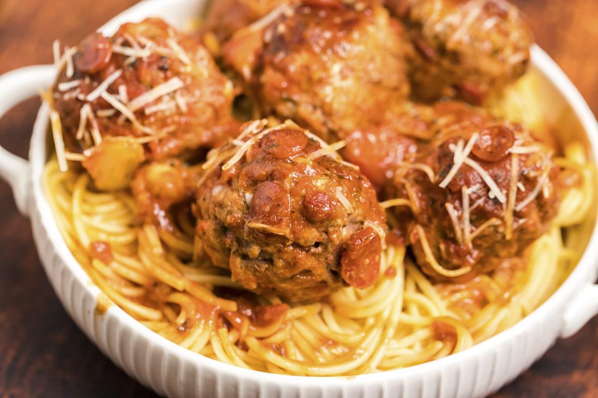Polpette di Pizza a Cottura Lenta 8 Una ciotola di spaghetti guarnita con succose polpette al sapore di pizza, pronte per un pasto completo e delizioso.