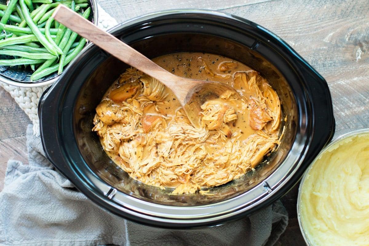 Pollo al Miele e Senape in Pentola a Cottura Lenta 8 Pollo al miele e senape cotto in slow cooker con cucchiaio di legno.