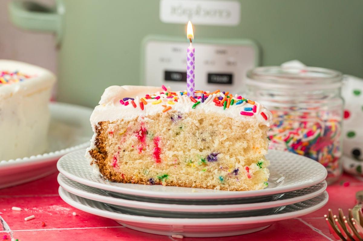 Fetta di torta di compleanno cotta nella slow cooker con una candela.