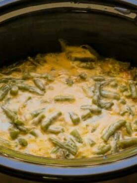 **Gratin di Fagiolini al Formaggio a Cottura Lenta** 8 Dettaglio della consistenza dei fagiolini al formaggio nella slow cooker, evidenziando la cremosità e il colore dorato della salsa.